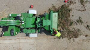 A person using a stump grinder to remove a tree stump in a grassy residential yard.